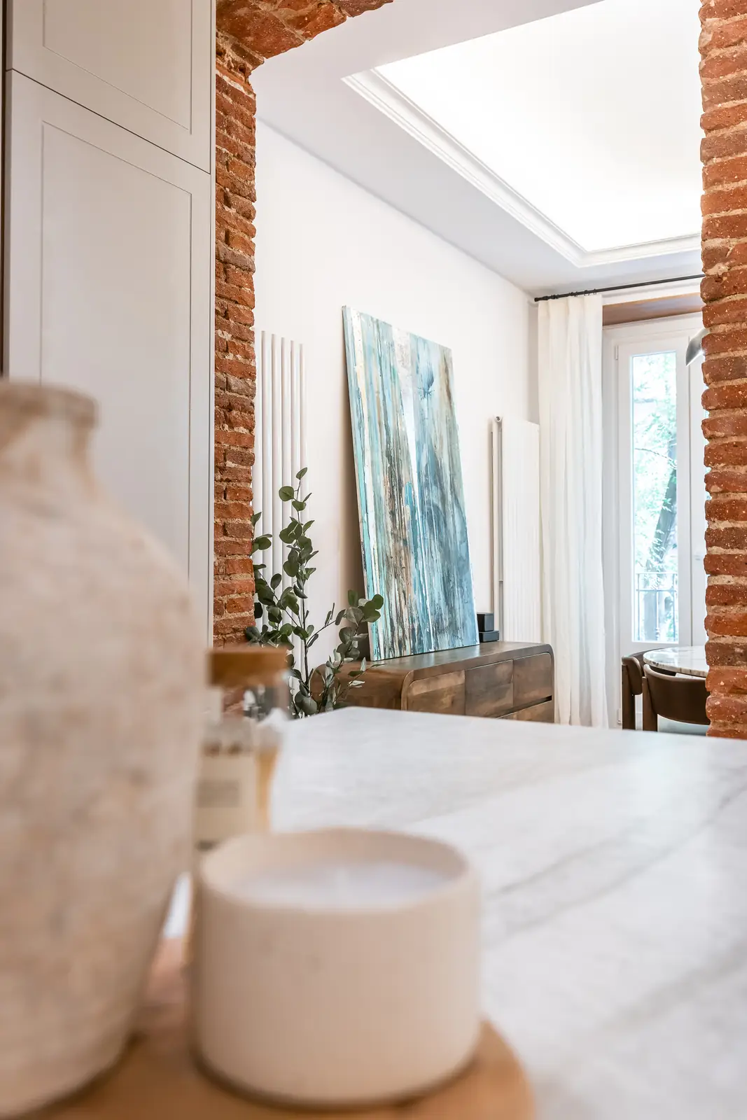 Cocina con isla de mármol, pared de ladrillo visto y obra de arte