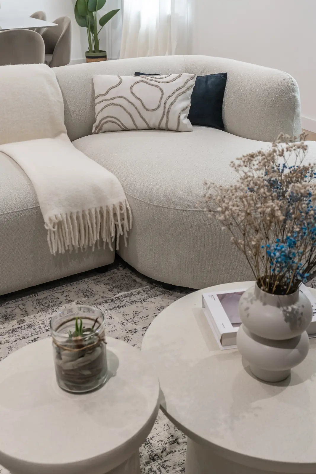 Salón moderno con sofá curvo beige y mesas de centro de mármol